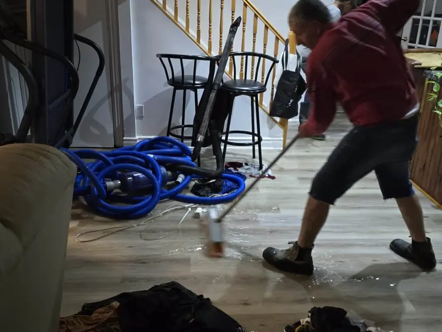 Squeegeeing standing water with extraction hoses in an Antioch, IL basement